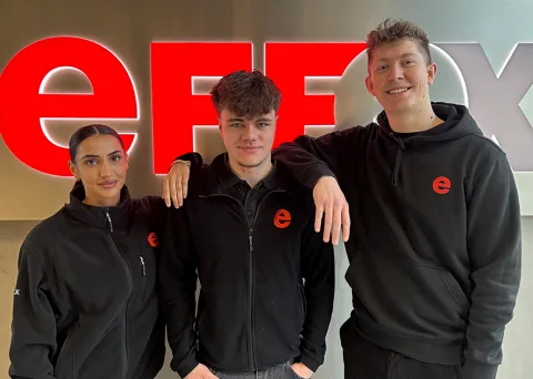 Drei Auszubildende posieren vor dem effexx Logo.