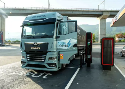 Ein LKW steht auf einem Parkplatz und lädt an einer e-Ladesäule