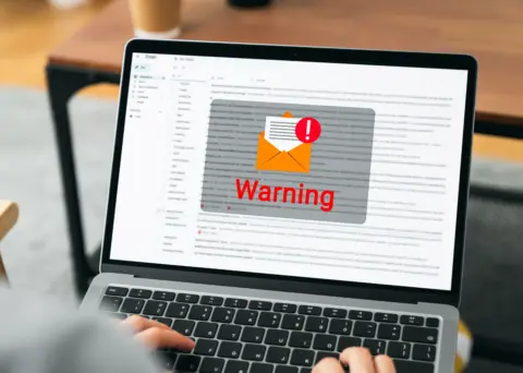 Person, die einen Laptop benutzt, auf dessen Bildschirm eine Warnmeldung angezeigt wird.