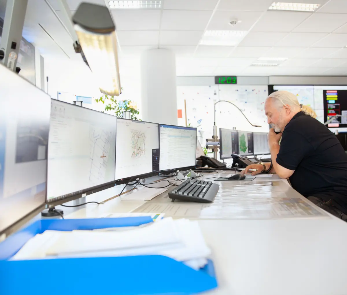 Ein Mann sitzt an einem Arbeitsplatz mit vielen Bildschirmen.
