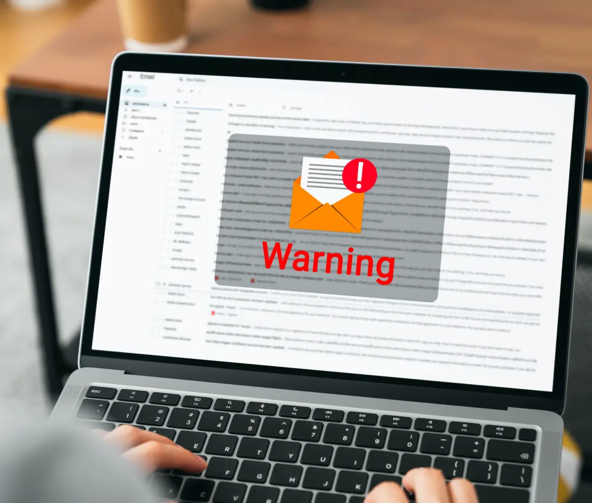 Person, die einen Laptop benutzt, auf dessen Bildschirm eine Warnmeldung angezeigt wird.